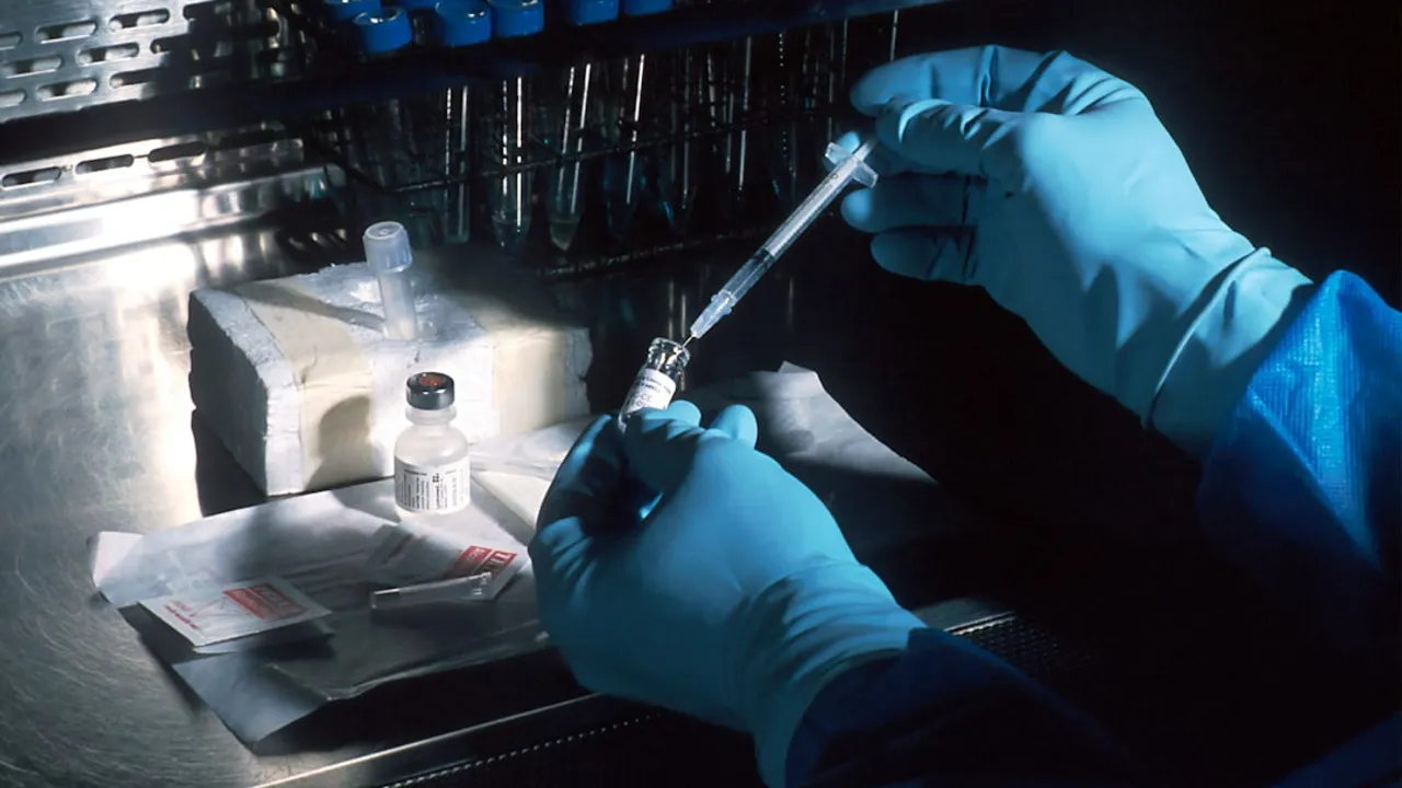 gloved hands drawing vaccine from vial with syringe