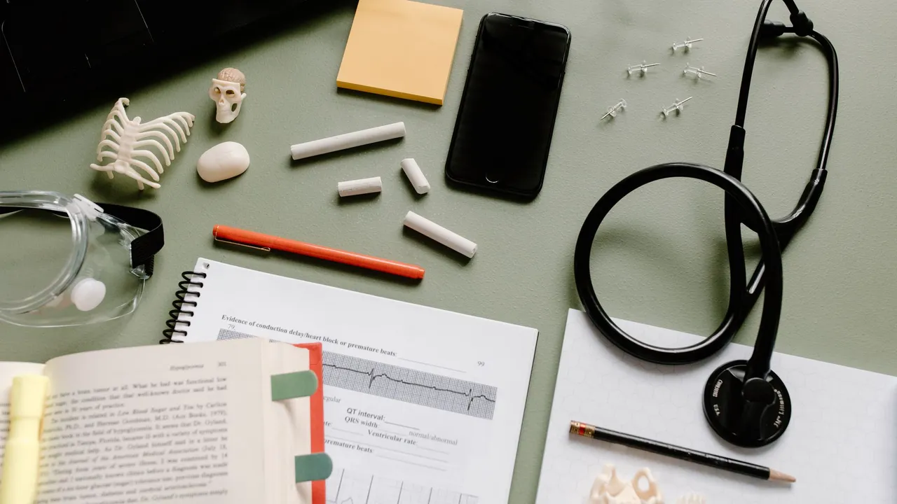 Flat lay of medical study desk with a stethoscope, books, and molecular models.